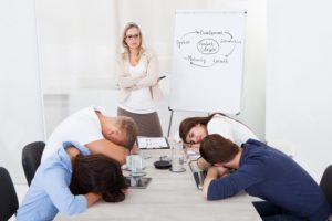 Angry businesswoman looking at tired colleagues sleeping during presentation in office